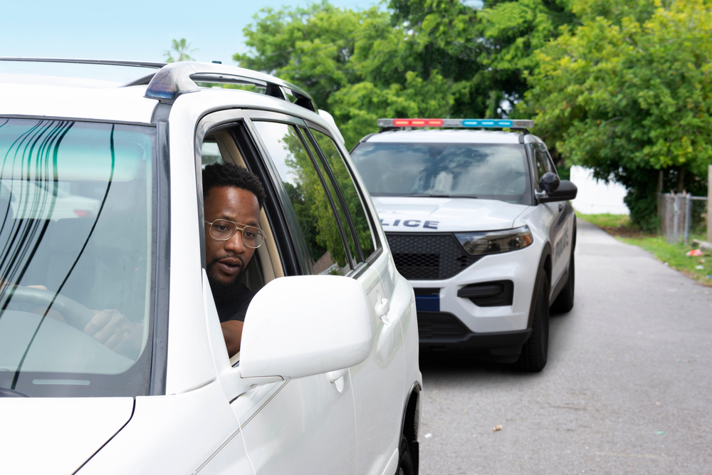 young black man with a very worried look on his face is looking at the police car